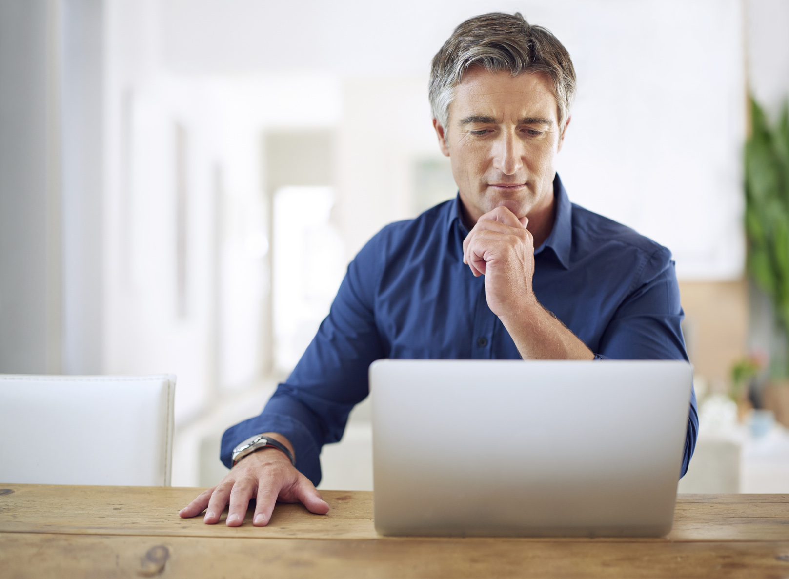 Man looking at a laptop computer screen and thinking